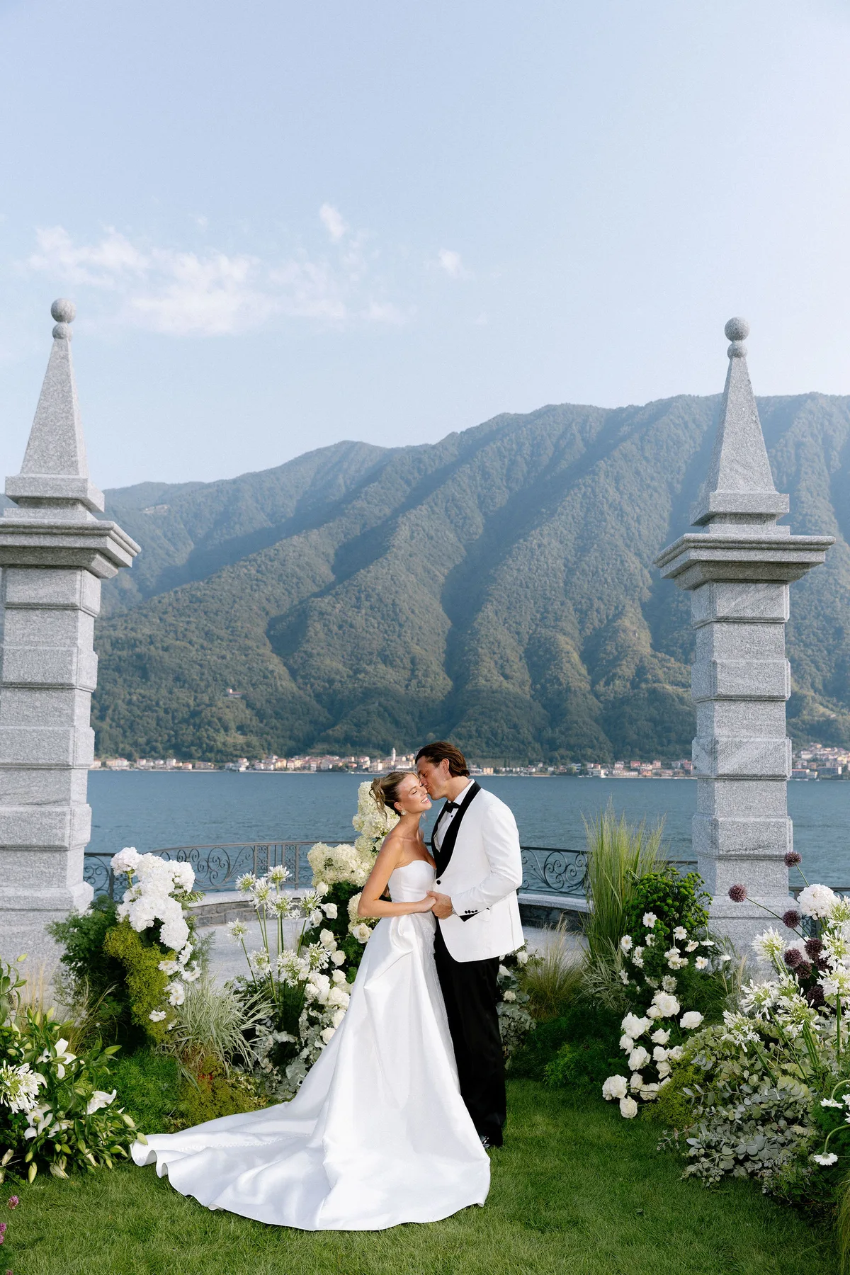 The couple kissing between two stone pillars, the lake and mountain beyond
