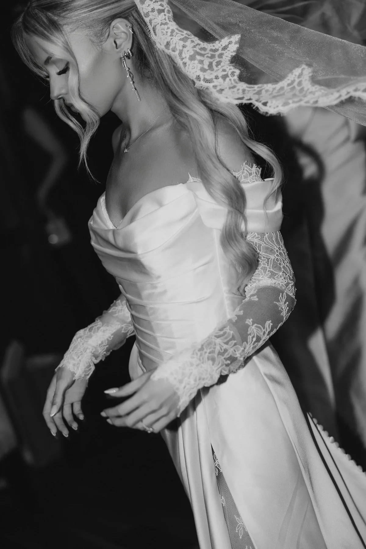The bride's hands and the fall of her satin skirt, her veil catching the light