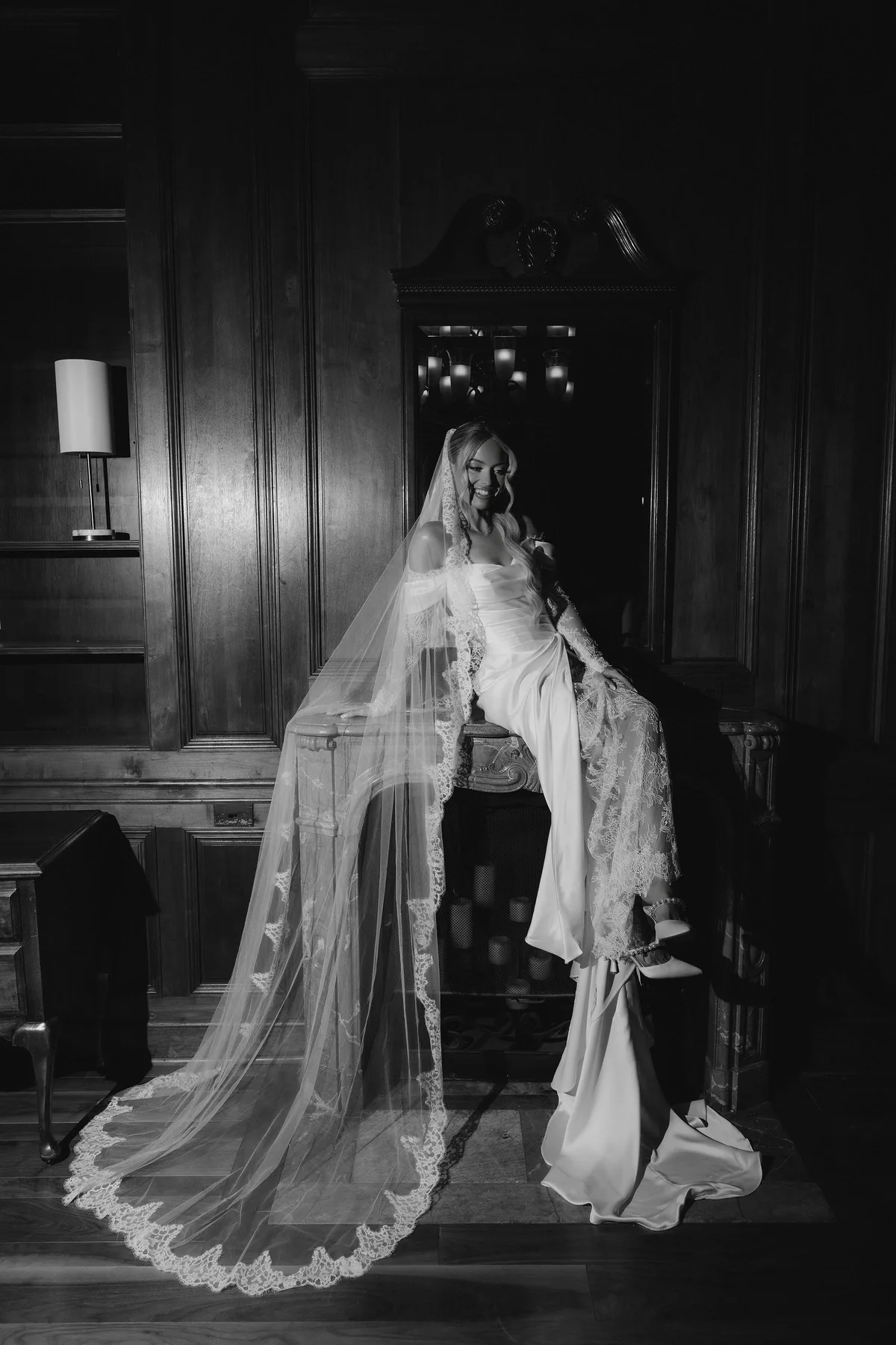 The bride on a staircase in a dark panelled hall, her veil falling down the steps