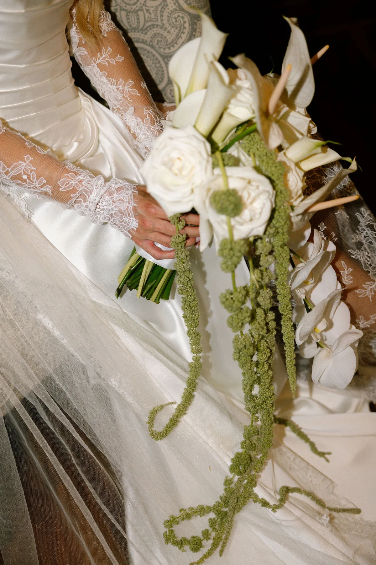 The bride's hands around a bouquet of calla lilies, roses and trailing amaranthus