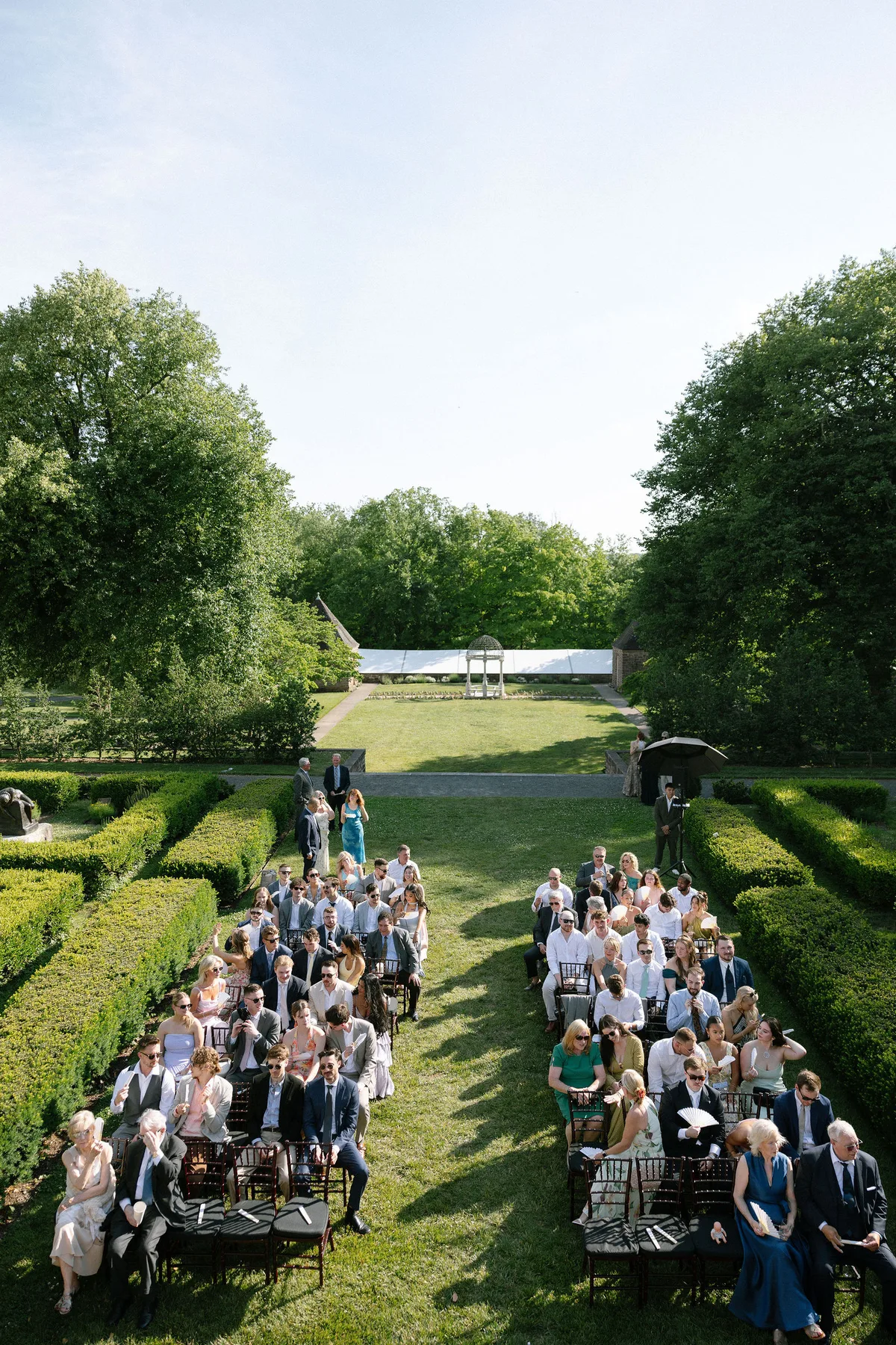 The ceremony from above: rows of guests between clipped hedges on the lawn
