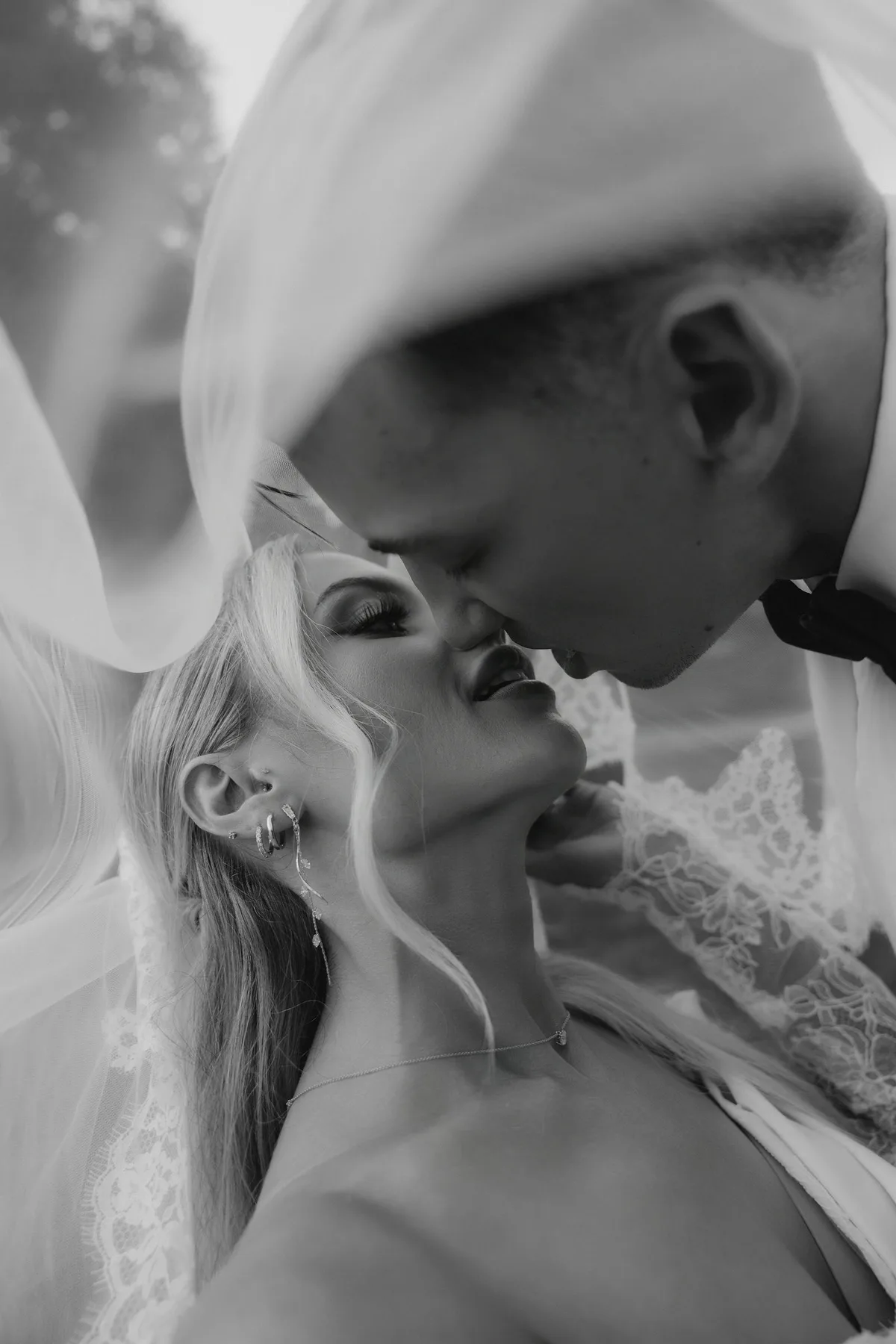 The couple kissing under her veil, close