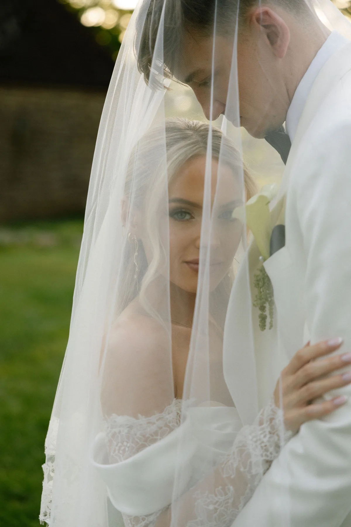 The bride looking out from under her veil, the groom's head bowed to hers