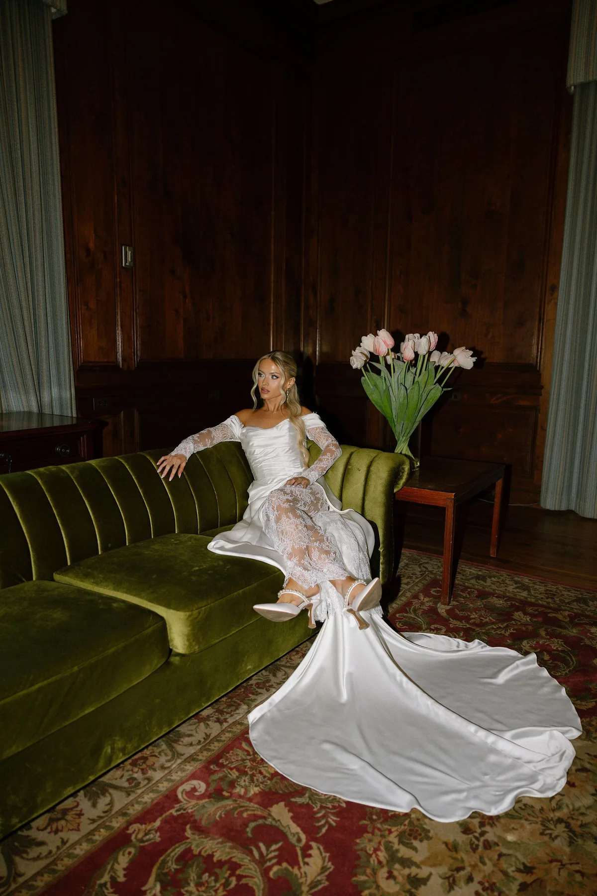 The bride on a green velvet sofa in a panelled room, tulips on the table