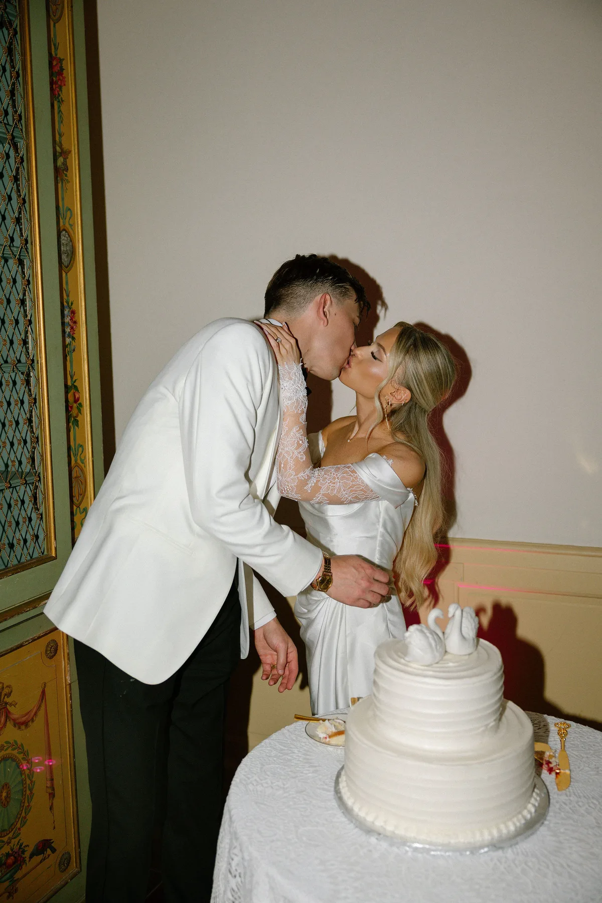 Bride and groom kissing over the cake, knife in hand