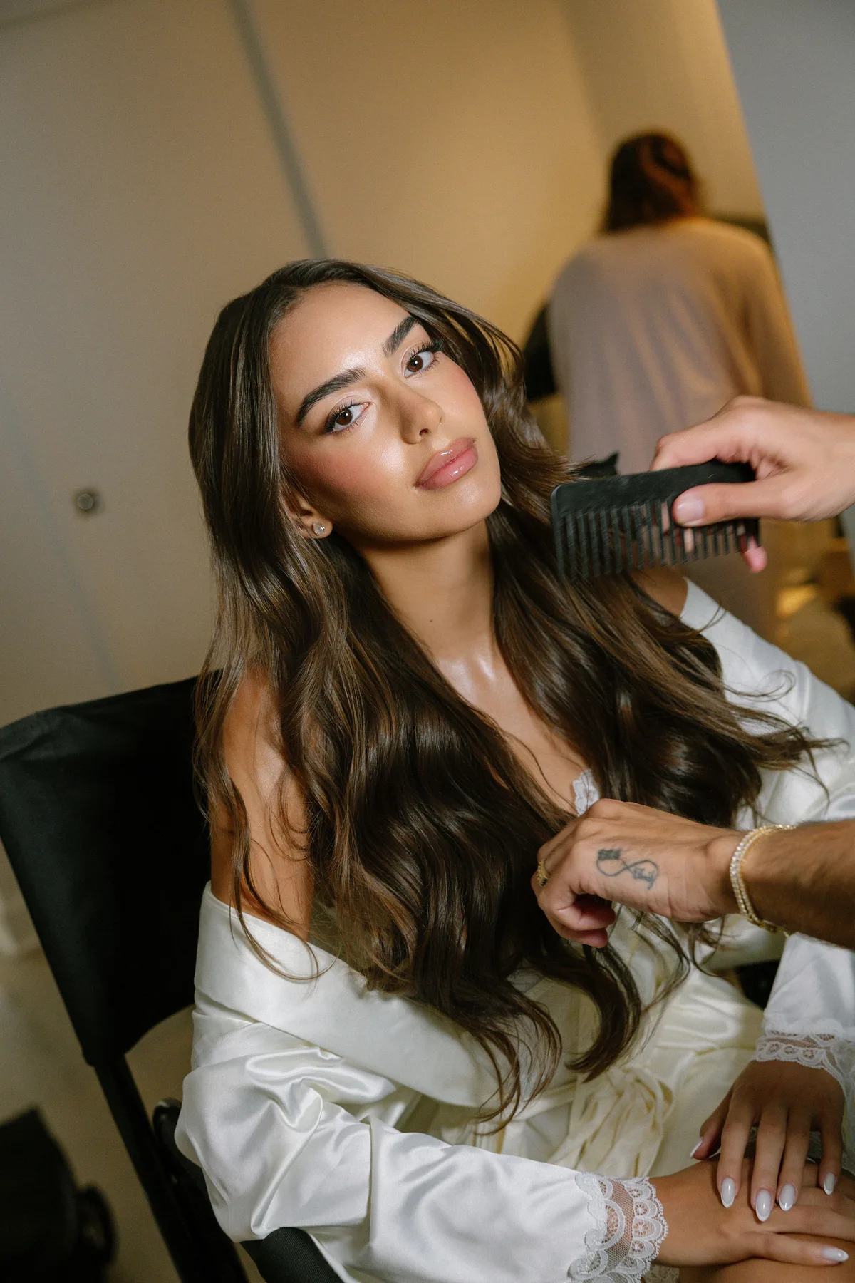 The bride's hair being combed in a satin robe before the ceremony