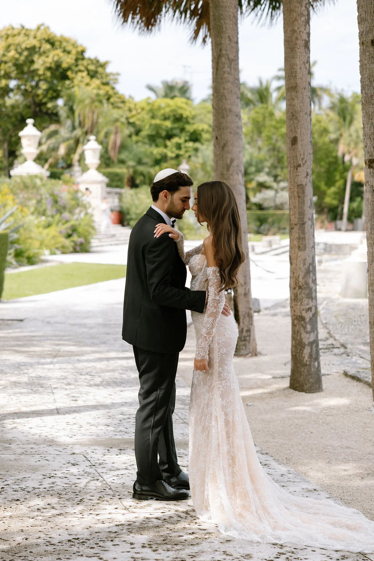 The couple standing forehead to forehead on a garden path
