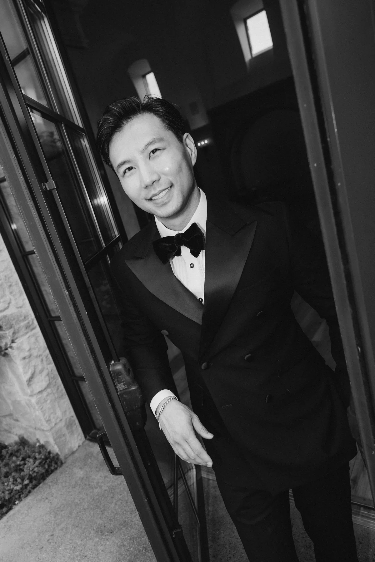 The groom in a double-breasted tuxedo in a doorway