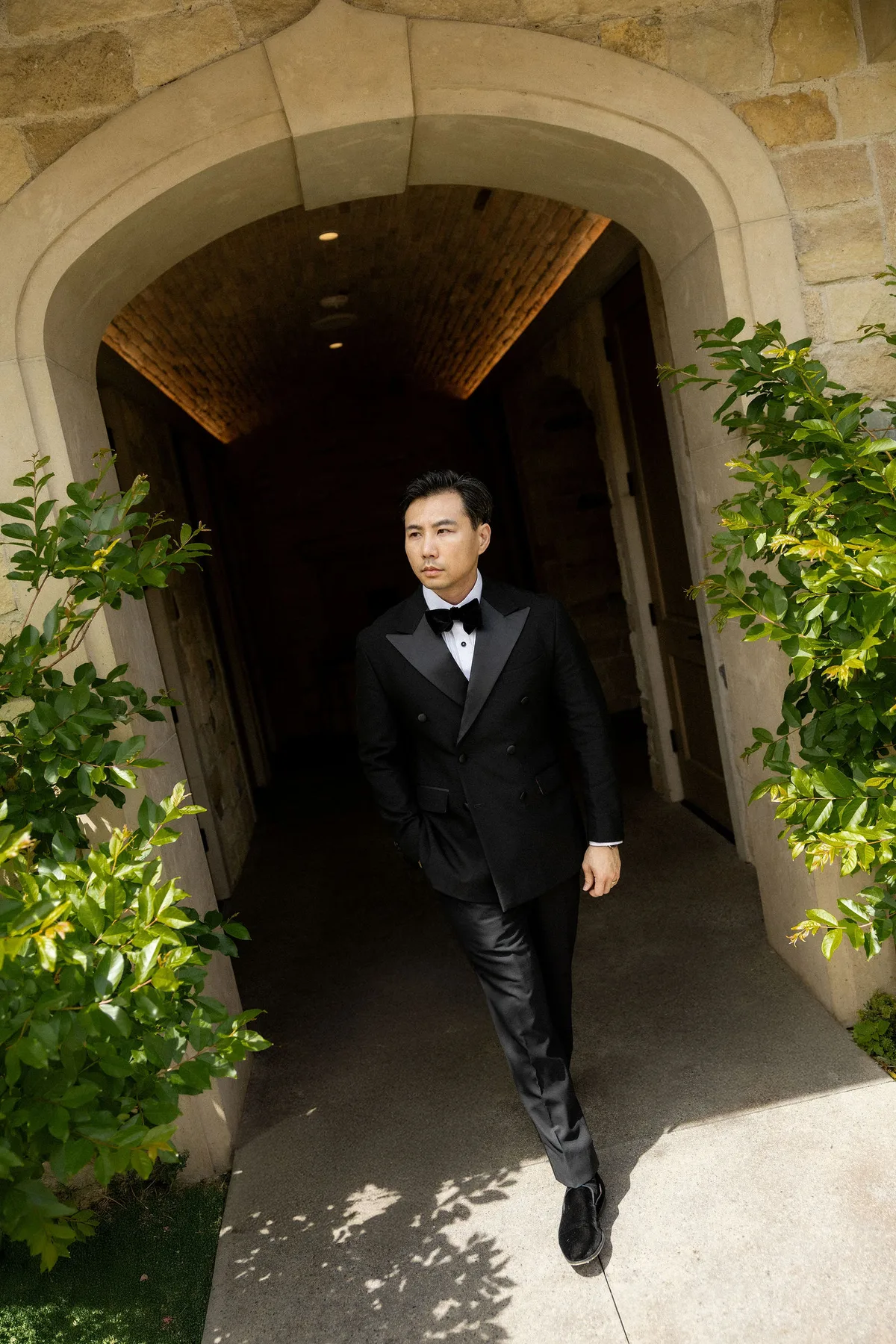 The groom walking out of a vaulted stone passage into the light