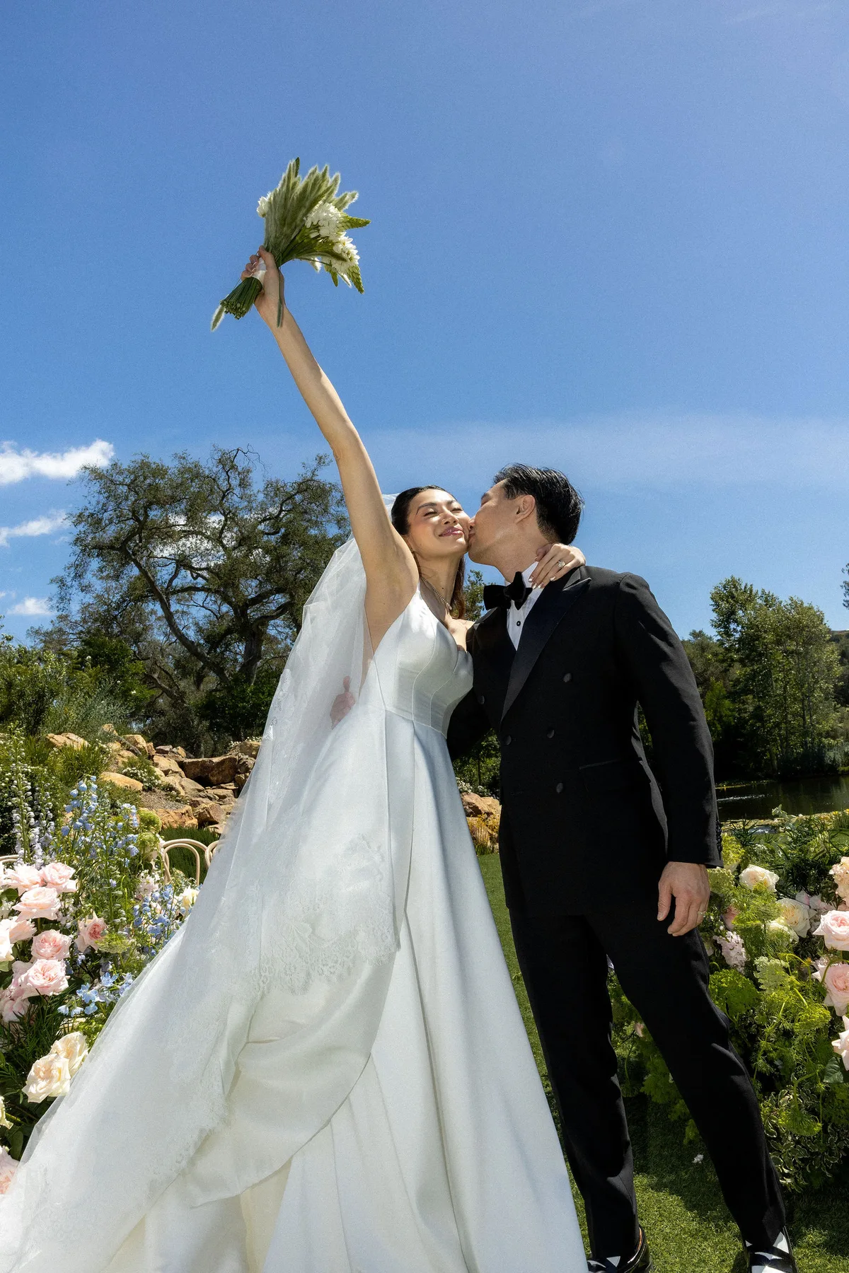 The bride throwing her bouquet arm up as the groom kisses her cheek