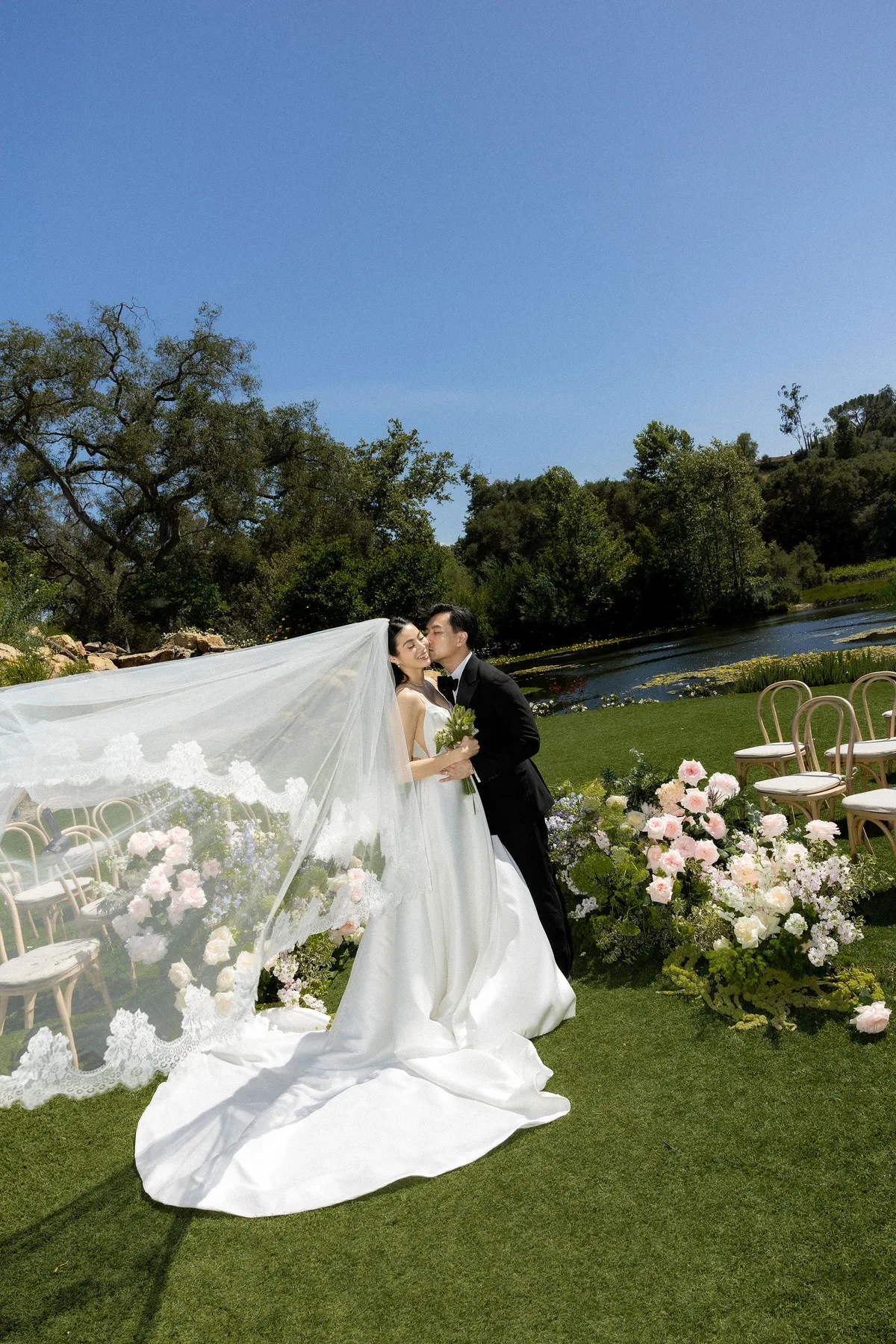 The couple at the end of the aisle, her veil swept across the flowers