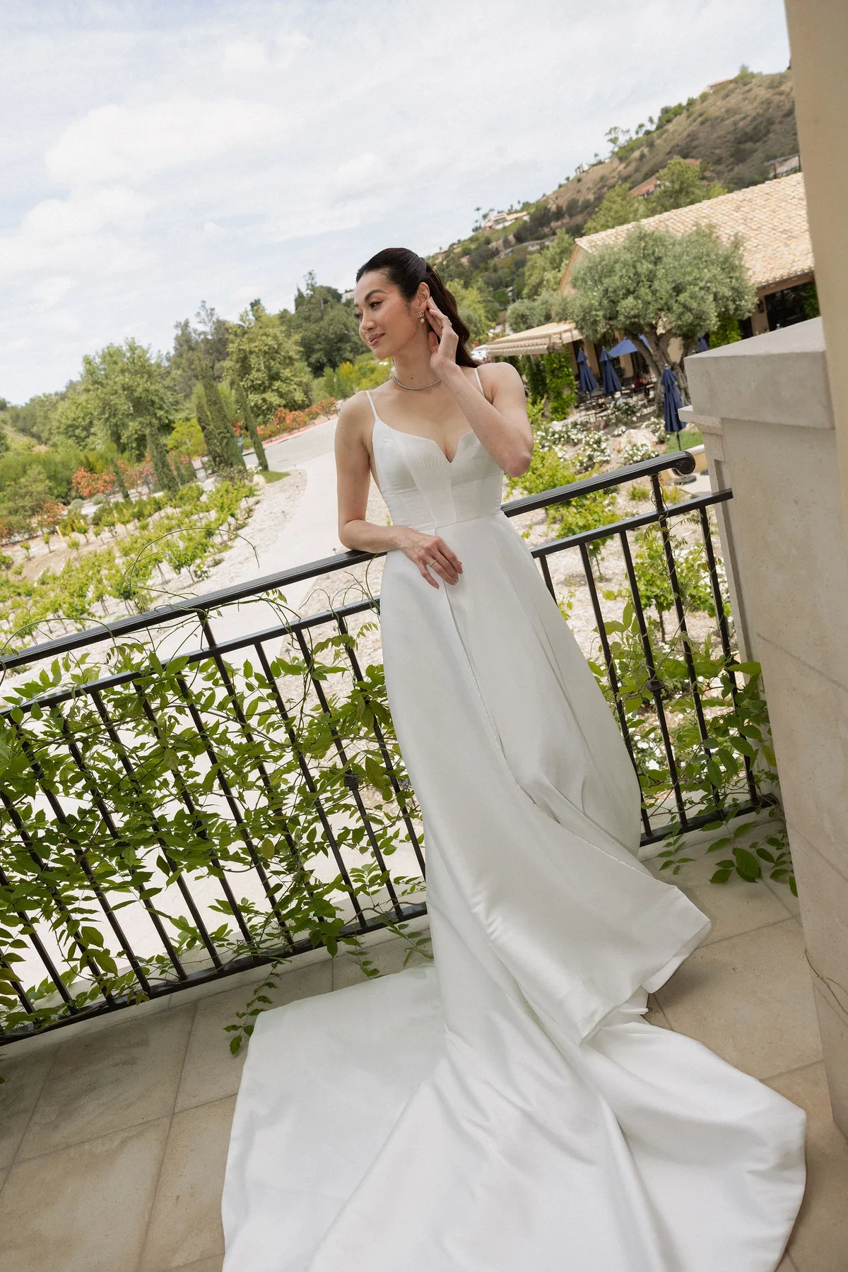 The bride on the terrace, her train sweeping the stone, the estate behind