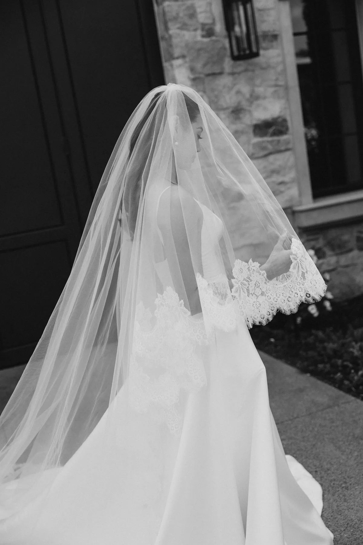 The bride from behind, her lace-edged veil over a full satin skirt
