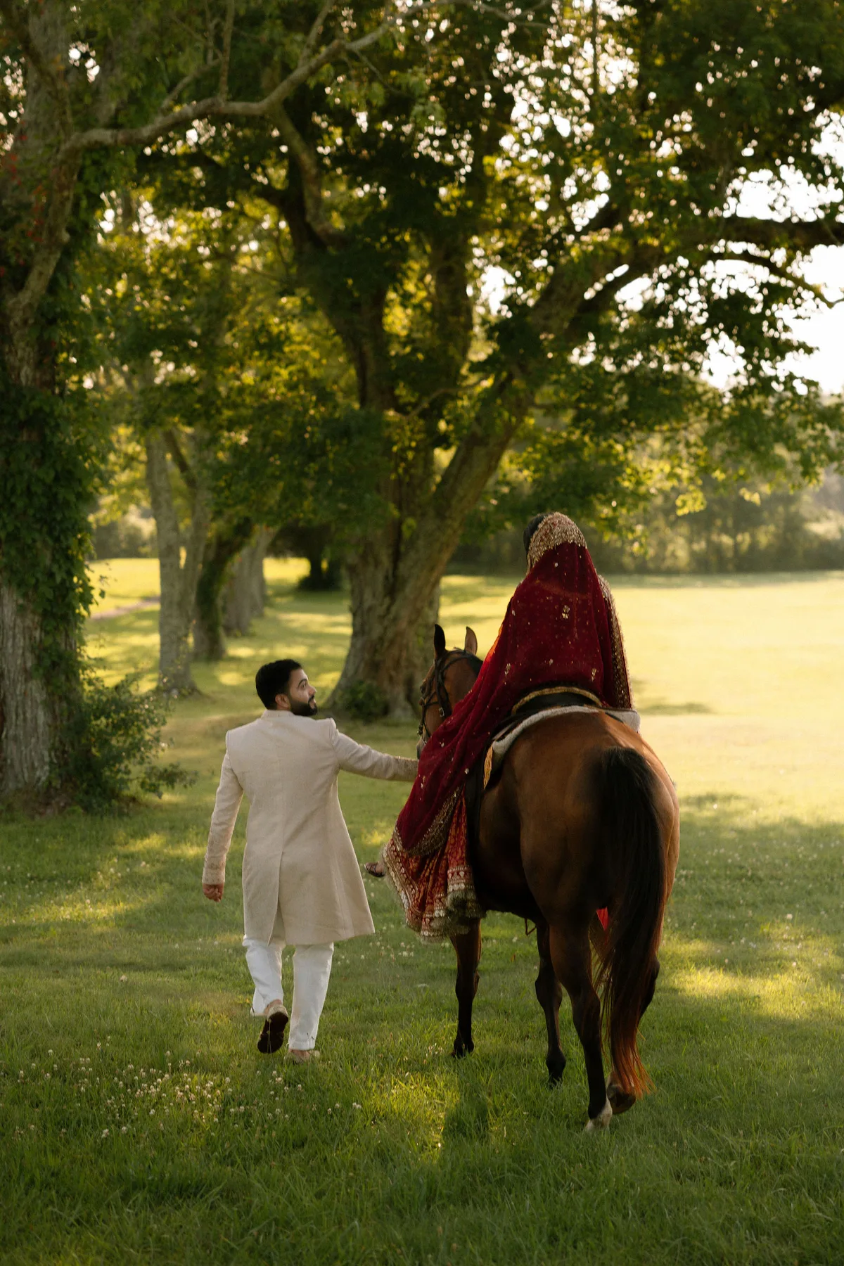 The groom leading the bride's horse away down an avenue of trees