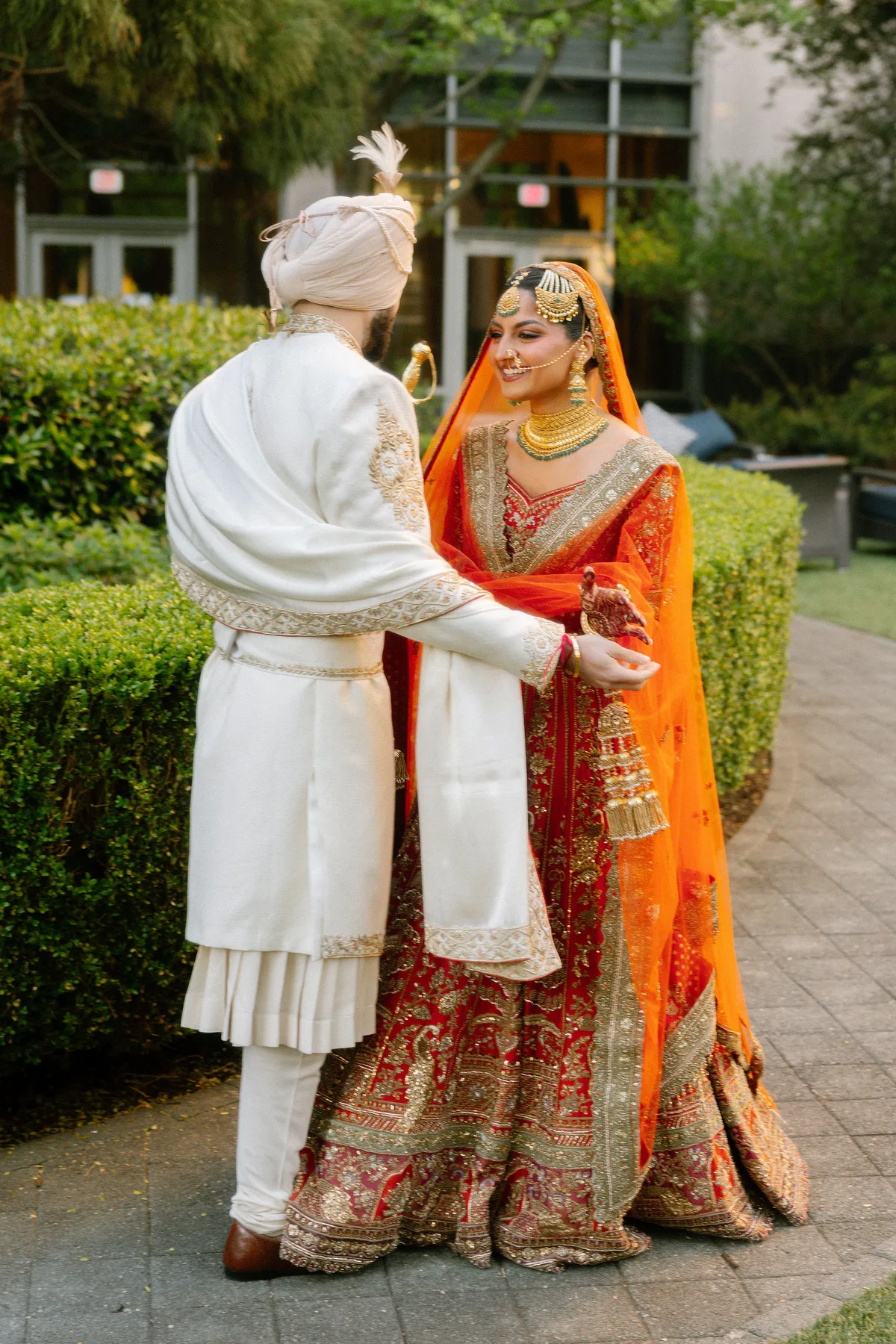 The couple from behind on a garden path, his shawl and her dupatta trailing