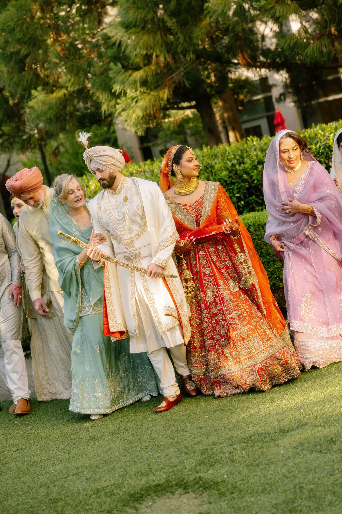 The groom walking with his family, the bride beside him in red