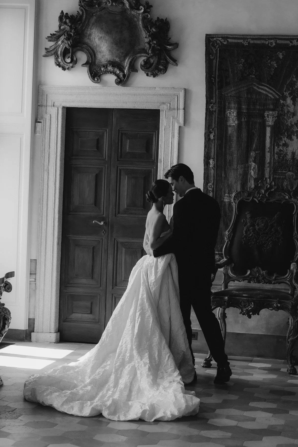 The couple in a panelled hall with carved mirrors, her train across the marble